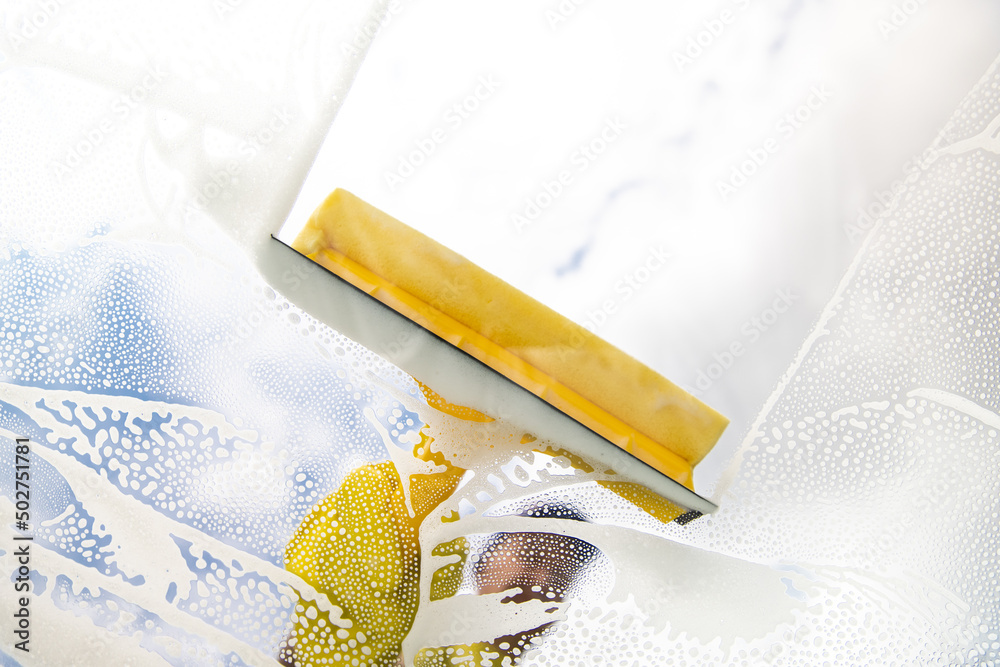 window cleaner cleaning window with squeegee and wipe