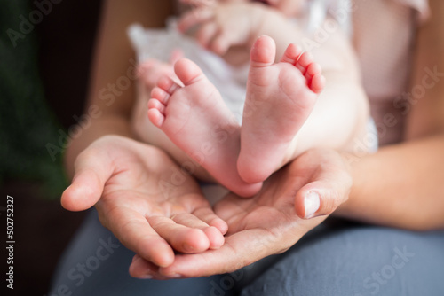 Rodzice trzymają w rękach swoje malutkie dziecko, stopy i rączki dziecka w dłoniach rodziców © Katarzyna Krociel
