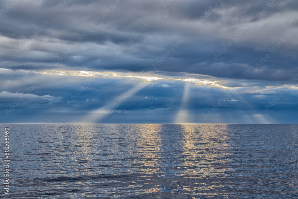 The sun's rays through a cloudy sky over the sea
