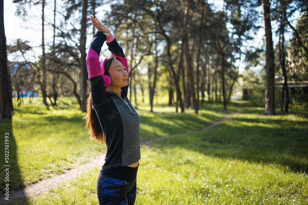 Woman runner stretching arms before exercising summer park morning.  female warming up body before running asian person warm up jogging 
