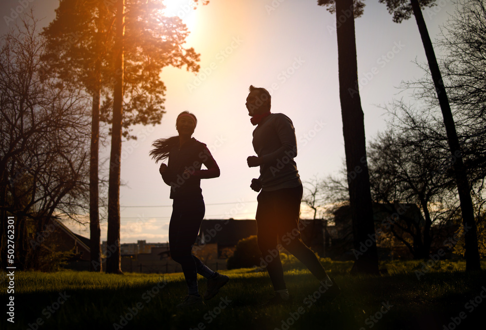 fitness, sport, people and lifestyle concept - couple running outdoors at sunset, silhouette image.