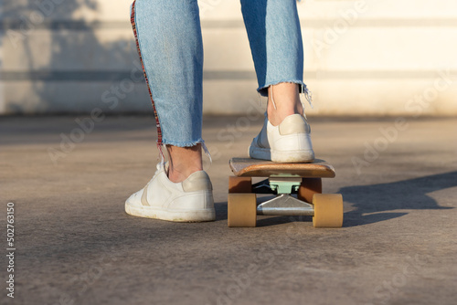 Cropped view of unrecognizable skater riding his skate board at the city park whearing sneaker and jeans