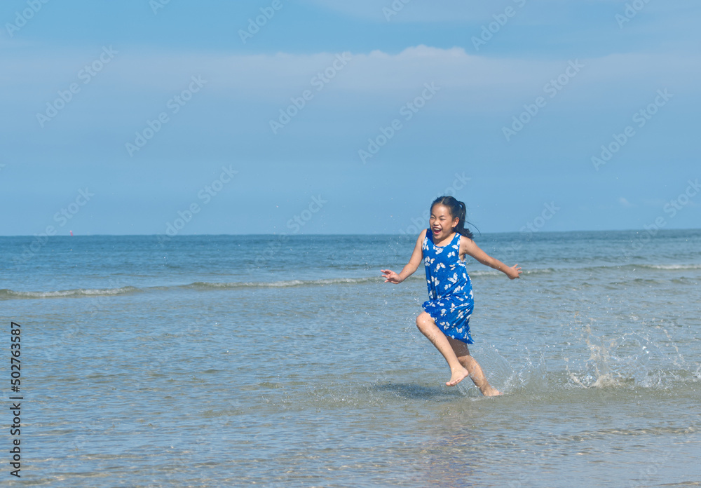 Asian little girl is running on the beach