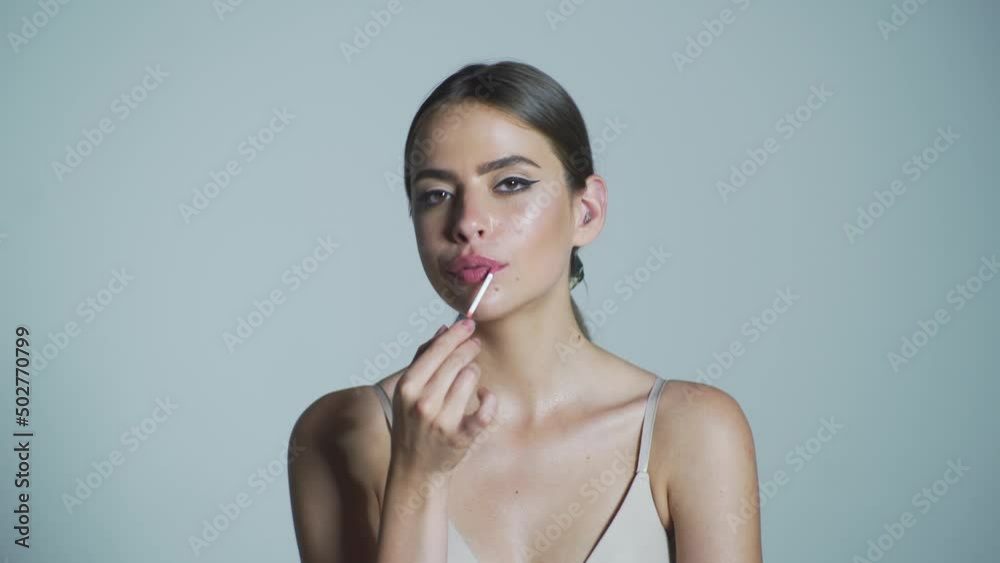Young woman applying lip gloss. Professional Make-up. Lipgloss. Lipstick. Beautiful young woman applying bright lipstick. Plump sexy full lips. Purple lipstick Young woman applying lip gloss. Professional Make-up. Lipgloss. Lipstick. Beautiful young woman applying bright lipstick. Plump sexy full lips. Purple lipstick