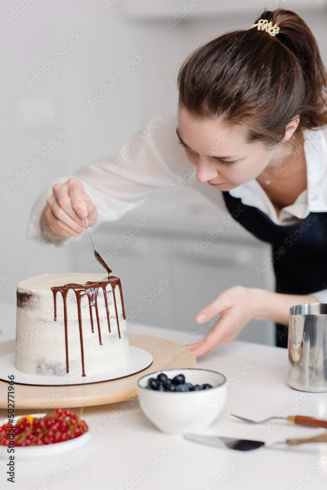 Happy good looking female pastry chef standing with her cake while making. Putting cream on a birthday cake. High quality photo Happy good looking female pastry chef standing with her cake while making. Putting cream on a birthday cake. High quality photo