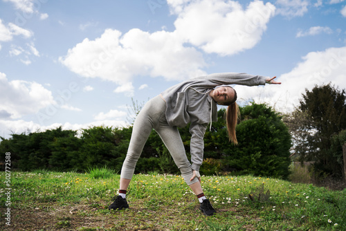 Strong teen girl standing and stretching herself at the park at open air