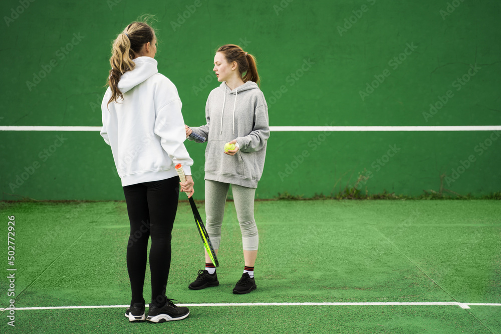 Cute teenage girl talking with her mother with rackets outdoors