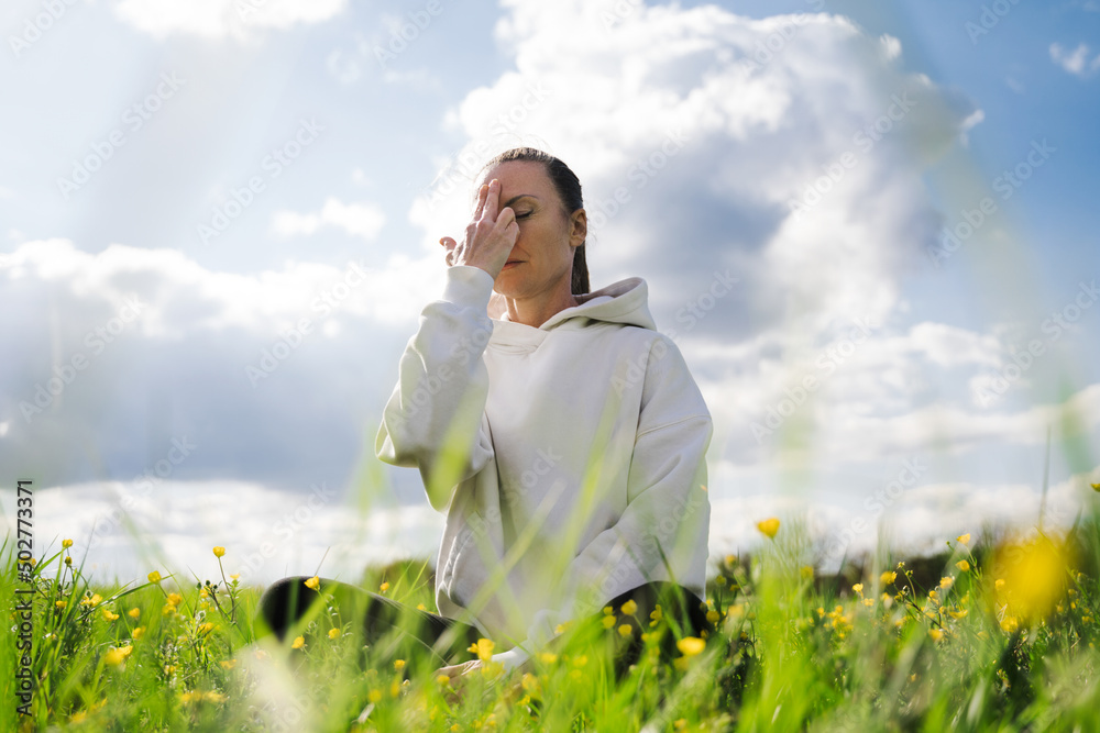 Woman keeping her eyes closed and doing breathing exercise while closes nostril Woman keeping her eyes closed and doing breathing exercise while closes nostril