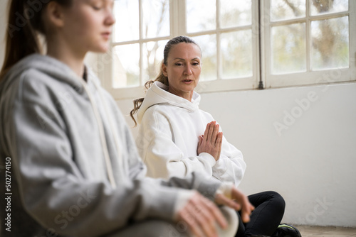 Mother and daughter sitting on the carry-mats and doing sport exercises