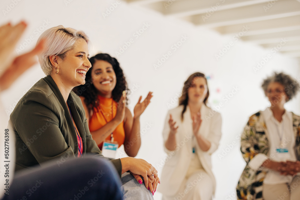 Obraz premium Smiling businesswomen applauding their colleague in an office