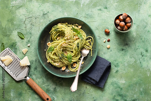 Ceramic plate with hazelnut pesto spaghetti on green table surface photo