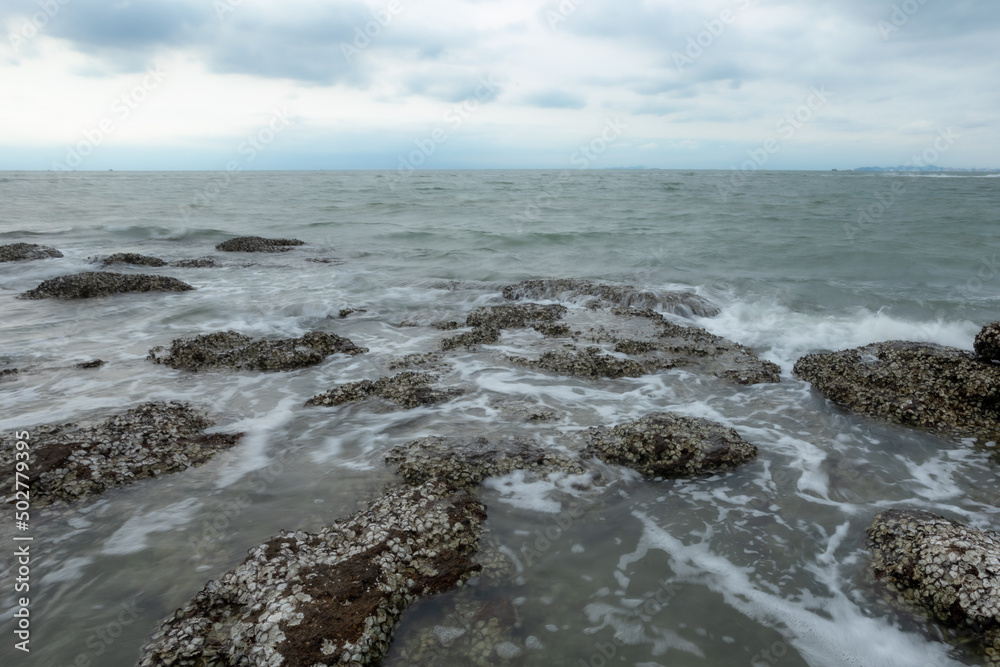 Ocean waves crashing against rocks on the sandy beach