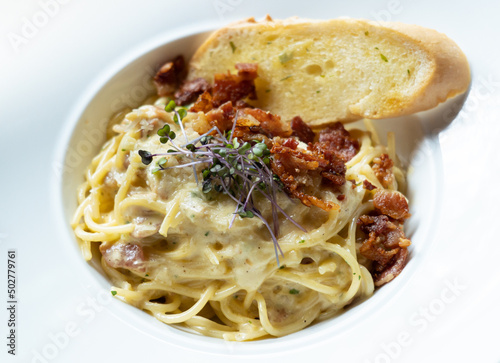 Spaghetti carbonara topped with crispy bacons and garlic bread