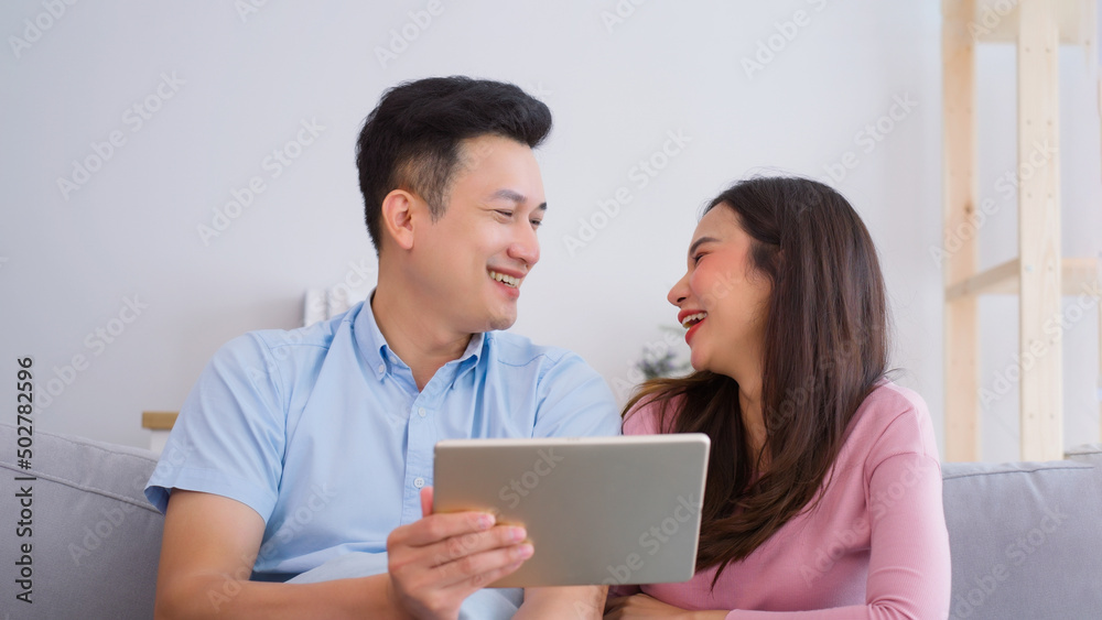 Young happy Asian couple using digital tablet relaxing on comfortable couch at home. technology, internet and people concept Young happy Asian couple using digital tablet relaxing on comfortable couch at home. technology, internet and people concept