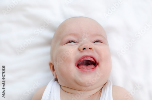 Infant laughing. Baby smiling with a toothless mouth close-up. Children healthcare