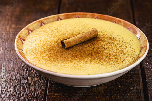 Bowl with corn jam called Curau, jimbelê or hominy, decorated with cinnamon in bark and cinnamon powder. Typical dessert of rural festivals in June and July