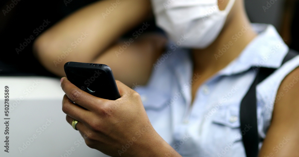 Commuter african woman wearing face mask checking cellphone while riding subway Commuter african woman wearing face mask checking cellphone while riding subway
