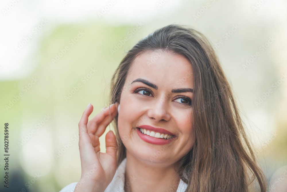 A young beautiful woman with long hair in comfortable light casual clothes listens to music using bluetooth headphones, walks in the center of a European city. A cute model is shopping. Spring. A young beautiful woman with long hair in comfortable light casual clothes listens to music using bluetooth headphones, walks in the center of a European city. A cute model is shopping. Spring.