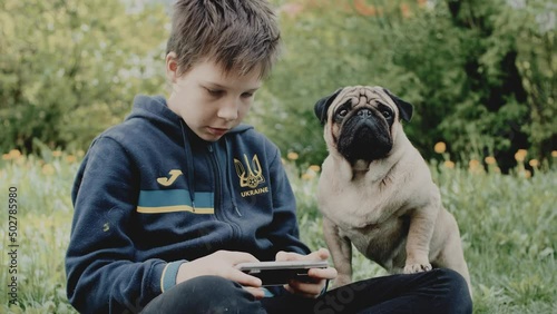 Ukrainian refugee boy playing video game on smarthphone photo