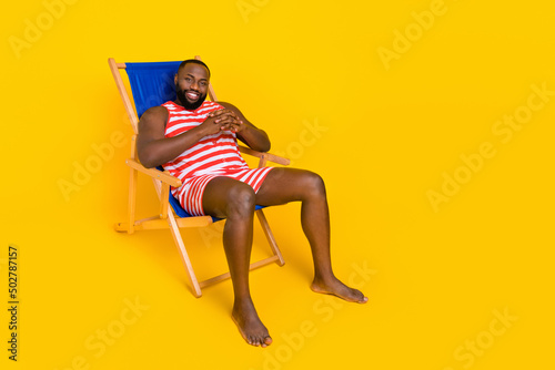 Fotografiet Photo of guy sit deck chair enjoy exotic recreation wear swim striped set shorts
