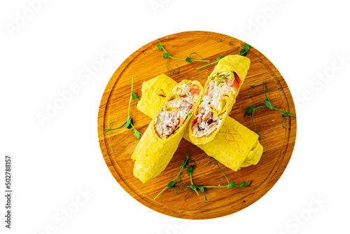 Shawarma doner with meat and vegetables lies on wooden plate isolated on white background