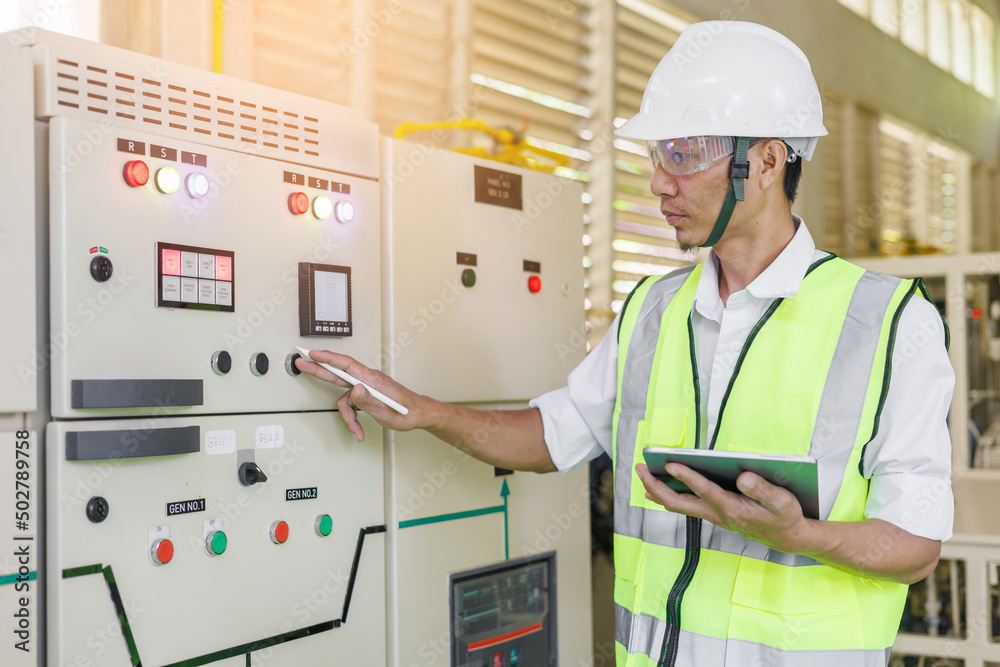 Electrical engineer holding tablet to inspecting the electrical system in a factory, energy concept. Electrical engineer holding tablet to inspecting the electrical system in a factory, energy concept.