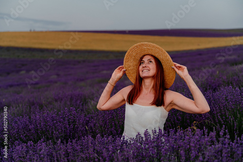 Close up portrait of a happy young woman in a dress on blooming fragrant lavender fields with endless rows. . Bushes of lavender purple fragrant flowers on lavender fields.