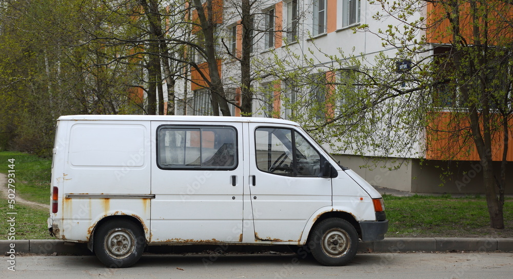 An old rusty white minibus parked on the road, Shotman Street, St. Petersburg, Russia, May 2022