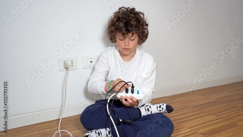 Obraz na płótnie 7-year-old child at home uses and plays with the electrical socket with the danger of getting shocked - domestic life in childhood w salonie