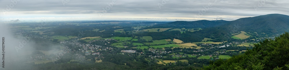 panorama view from hill to valley with rolling clouds over small town