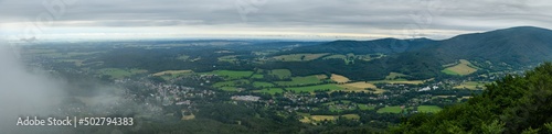panorama view from hill to valley with rolling clouds over small town