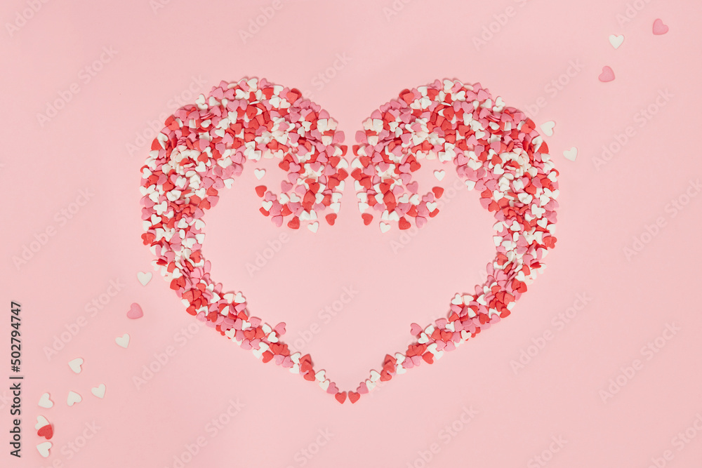 Love heart from Candies hearts of pastel colors on pink paper. Top view. Valentine's Day, background. Valentine day greeting card or banner.