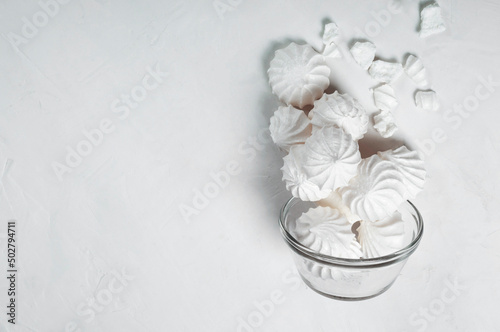 on a flat surface, a French meringue dessert is poured into a glass bowl. imitation of levitation. Meringue is made from a mixture of beaten egg whites with sugar. copy space.