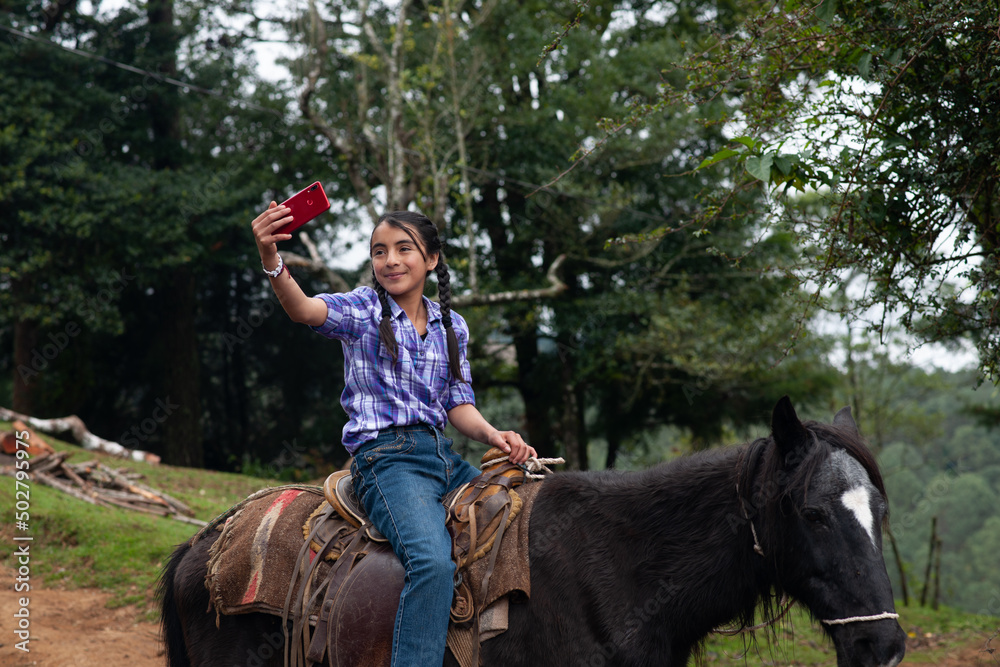 A girl takes a selfie on her smartphone while riding through the woods. A girl takes a selfie on her smartphone while riding through the woods.