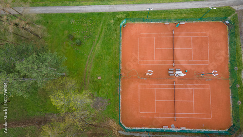 aerial drone view from above on tennis court between trees of a forest