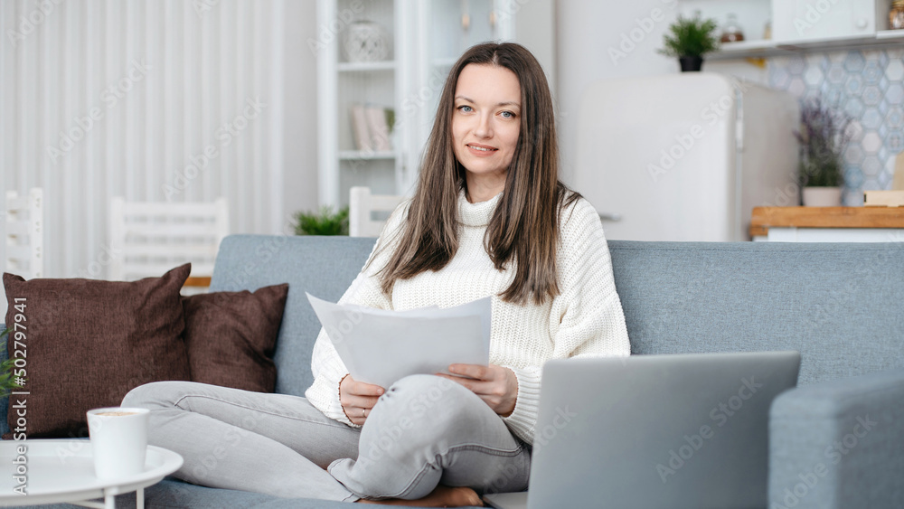 young woman reading a business document sitting on the sofa young woman reading a business document sitting on the sofa