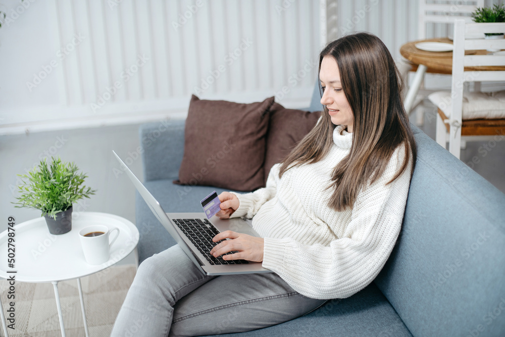 smiling woman with a credit card using a laptop in a cozy living room. smiling woman with a credit card using a laptop in a cozy living room.