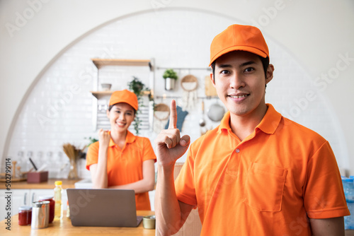Handsome Asian delivery man in an orange uniform hands up for show number one to build confidence for cook customers in kitchen. Domestic and international transport and logistics