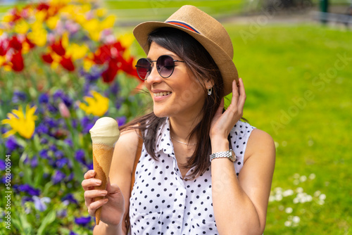 Tourist woman enjoying visiting the city eating a pistachio ice cream, enjoying summer vacations and having a camera, solo female traveler concept