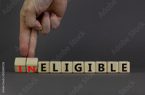 Eligible or ineligible symbol. Businessman turns wooden cubes and changes words Ineligible to Eligible. Beautiful grey table grey background. Business eligible or ineligible concept. Copy space. photo