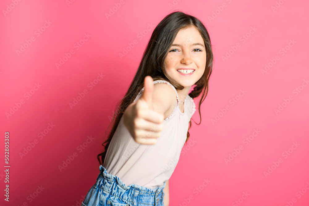 cute positive thumb up child over pink backgroud on studio cute positive thumb up child over pink backgroud on studio
