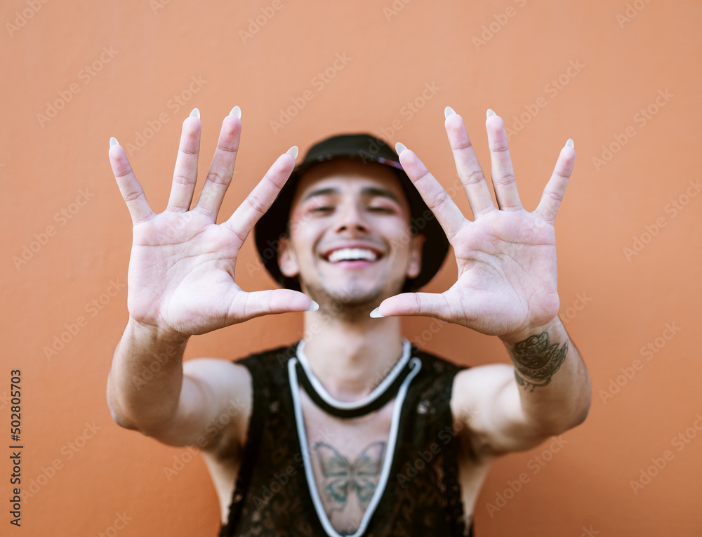 Young man with tattoos extending his arms while smiling and showing his long fingernails. Lgbti community and lifestyle. Young man with tattoos extending his arms while smiling and showing his long fingernails. Lgbti community and lifestyle.