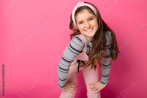 cute child with dungarees over pink background on studio