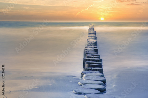 Fototapeta Naklejka Na Ścianę i Meble -  Groynes protruding into the horizon in the Baltic Sea. Long exposure with muted colors.