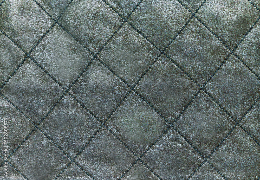 Fototapeta premium Green quilted genuine leather background, close up
