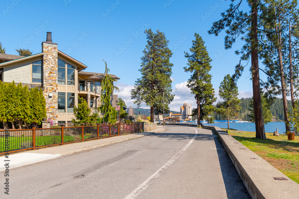 Luxury waterfront homes face the lake with the city beach, park and downtown resort and marina in view in Coeur d'Alene, Idaho, USA.