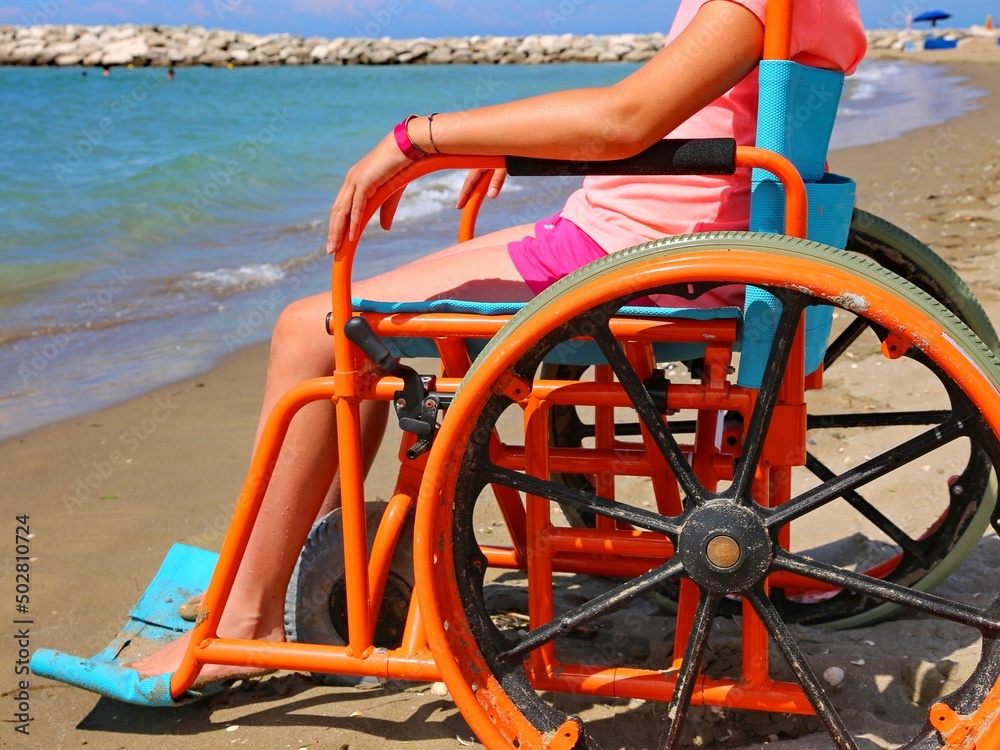 girl in a wheelchair with wheels modified to move on the beach