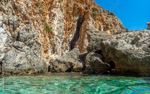 Transparent, cool sea under cliffs and clear blue sky. Summer in Greece.