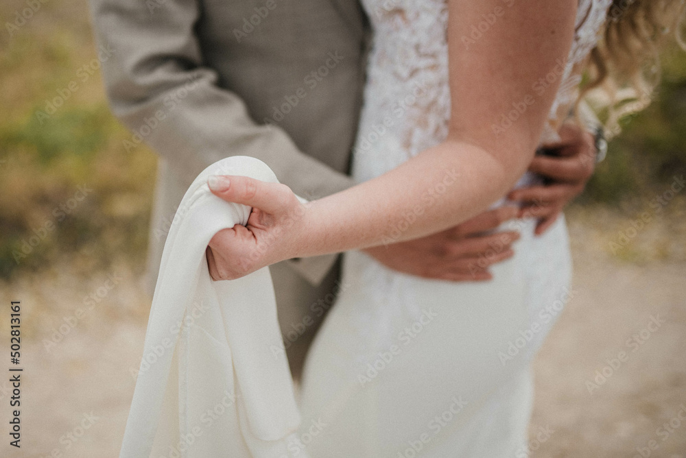 Obraz premium Bride in beautiful white wedding dress with bouquet and elegant groom in suit at happy wedding day. 