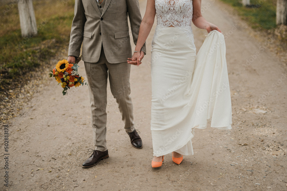 Obraz premium Bride in beautiful white wedding dress with bouquet and elegant groom in suit at happy wedding day. 